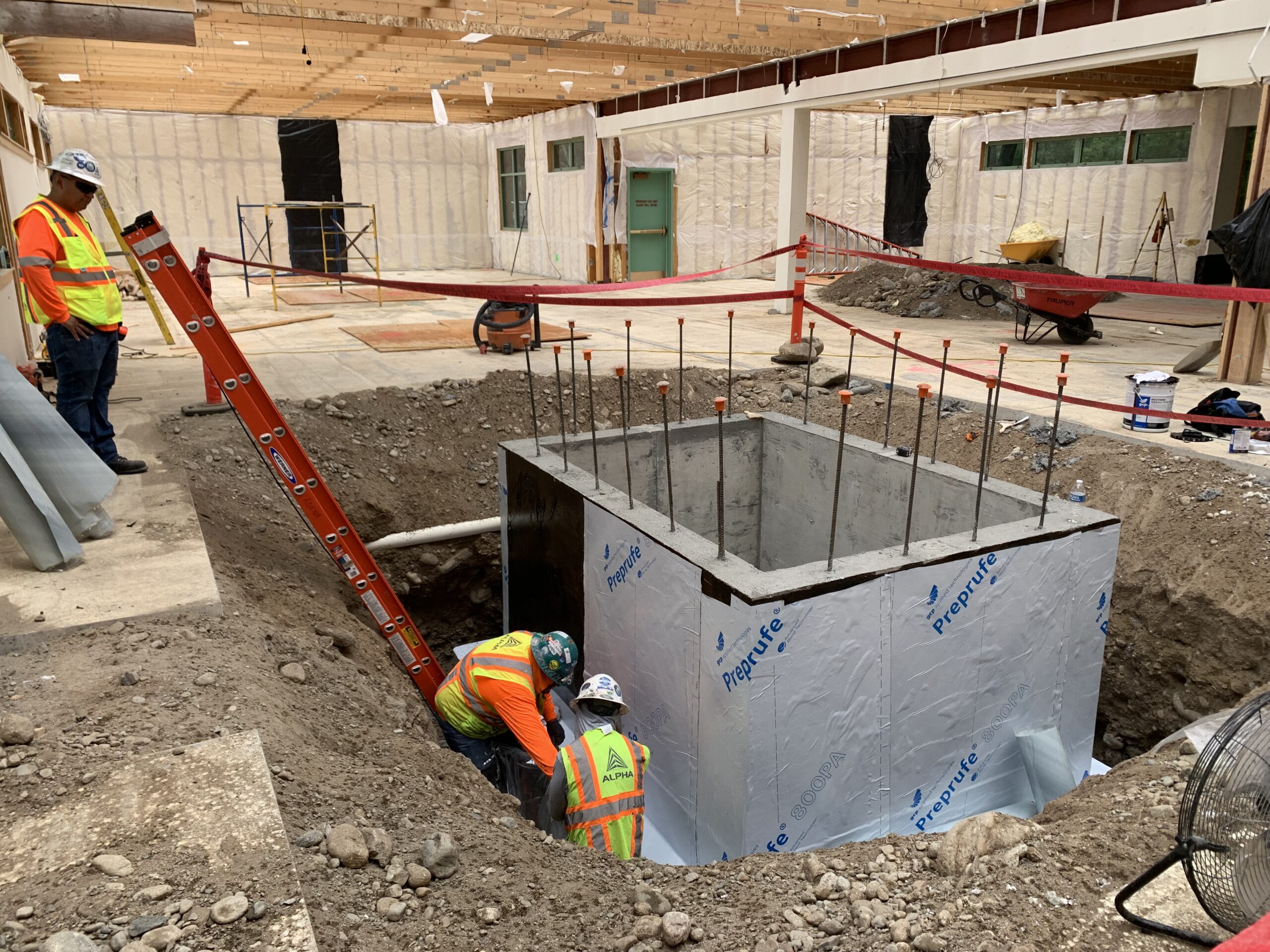 Crews work to waterproof the elevator pit walls.